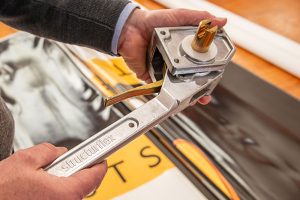 Technician tightening a curtain sider trailer tensioner to secure the trailer curtain for safe cargo transportation.