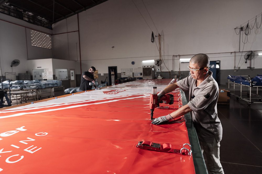 Technician heat welding a custom PVC truck curtain during the manufacturing process for a durable curtain sider system.